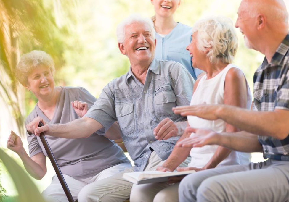 Four elderly people talking with worker behind.