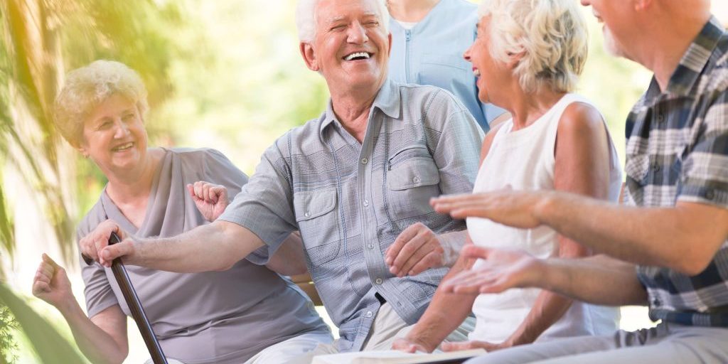 Four elderly people talking with worker behind.