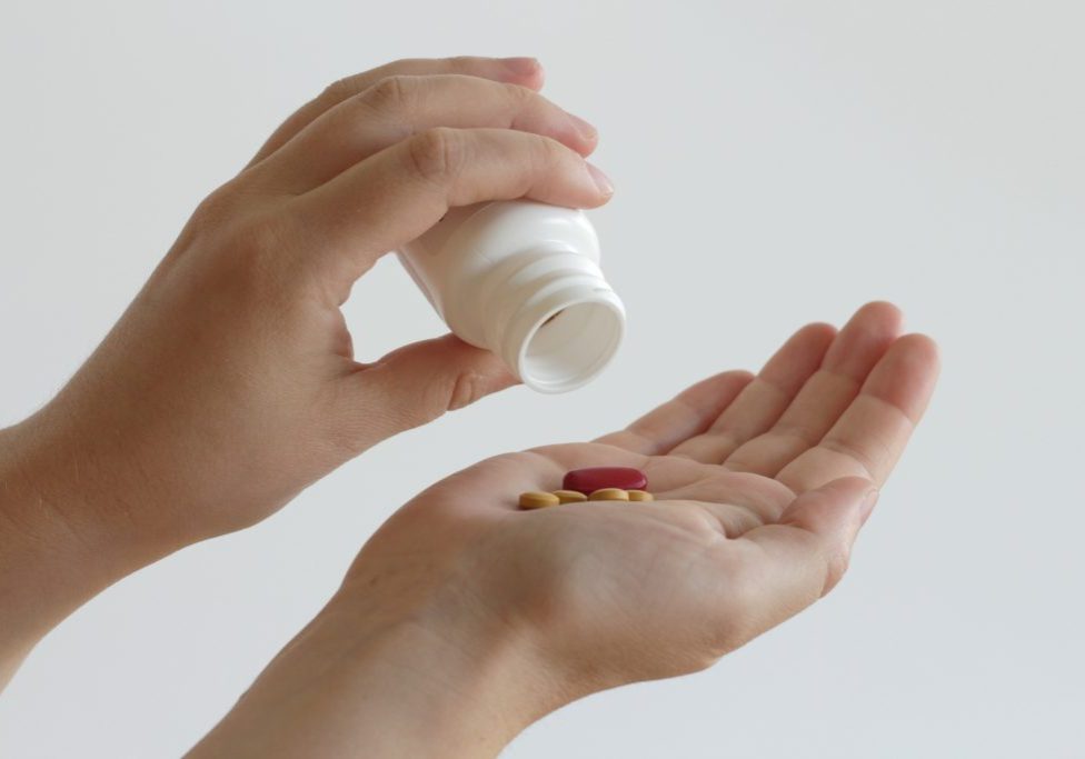 pouring out pills into hand from a plastic container
