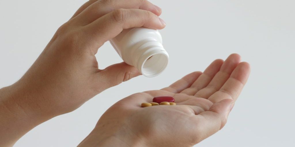 pouring out pills into hand from a plastic container